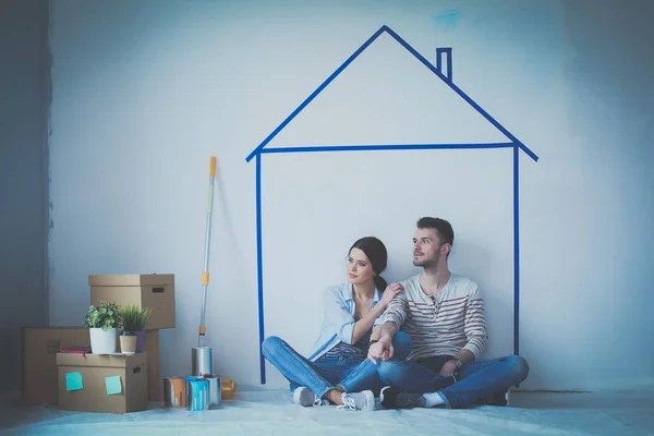 Couple sitting in front of painted home on wall — Stock Photo, Image