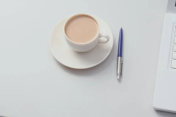 Une tasse de café, du papier et un stylo sur un ordinateur portable — Photo