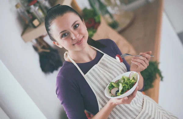 Jonge vrouw die verse salade eet in de moderne keuken — Stockfoto