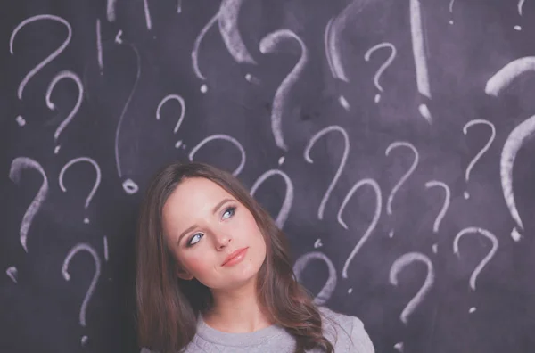 Ung flicka med frågetecken på en grå bakgrund — Stockfoto