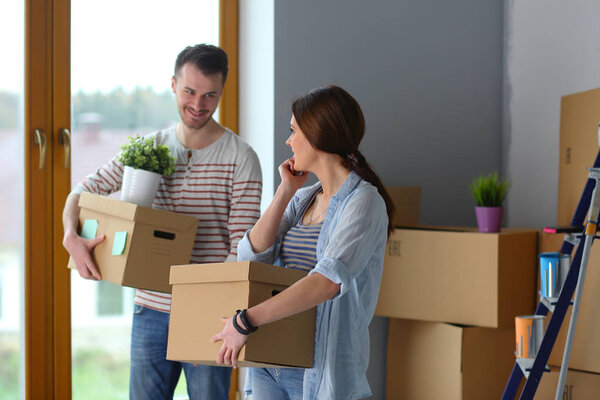 Счастливая молодая пара распаковывает коробки и переезжает в новый дом
