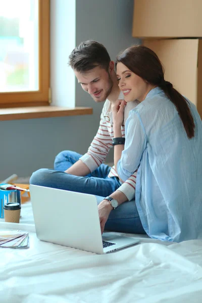 Jeune couple assis sur le sol de leur nouvel appartement — Photo