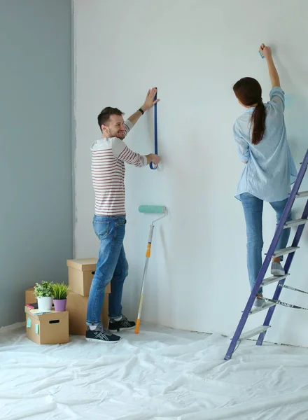 快乐微笑着对年轻的夫妇内墙绘画新房子的肖像 — 图库照片