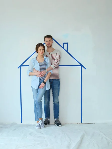 Couple standing in front of painted home on wall — Stock Photo, Image