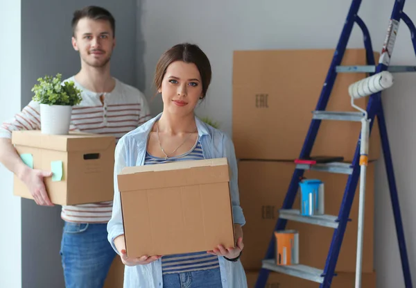 Feliz pareja joven desempacar o empacar cajas y mudarse a un nuevo hogar — Foto de Stock