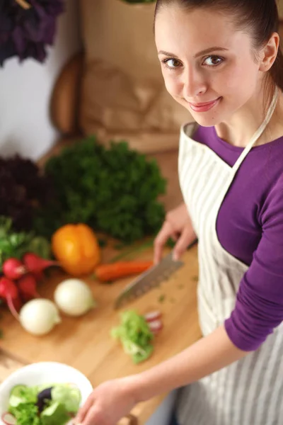 Mujer joven cortando verduras en la cocina — Foto de Stock