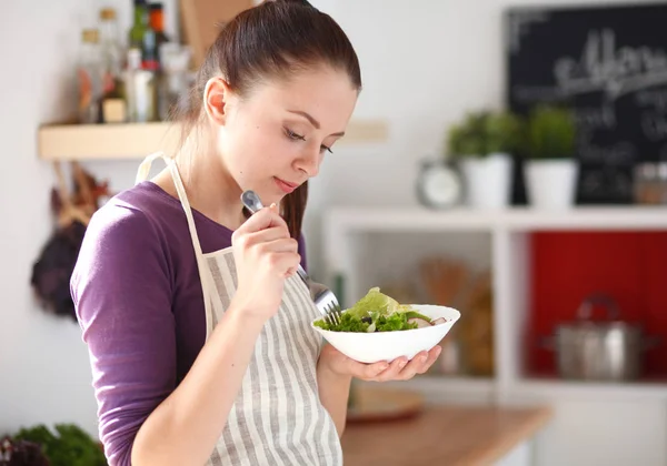 Jonge vrouw die verse salade eet in de moderne keuken — Stockfoto