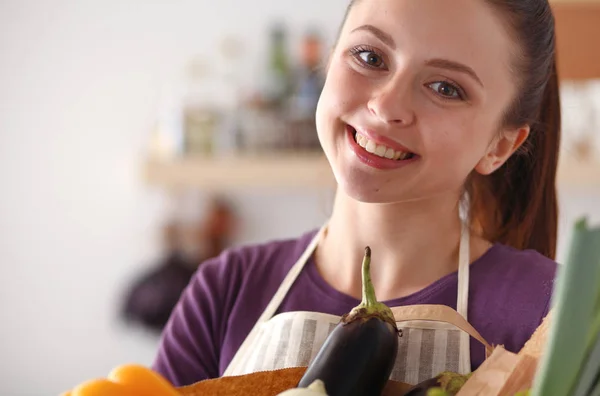 Jonge vrouw met boodschappentas met groenten Staande in de keuken — Stockfoto