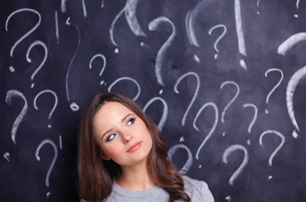 Chica joven con signo de interrogación sobre un fondo gris — Foto de Stock