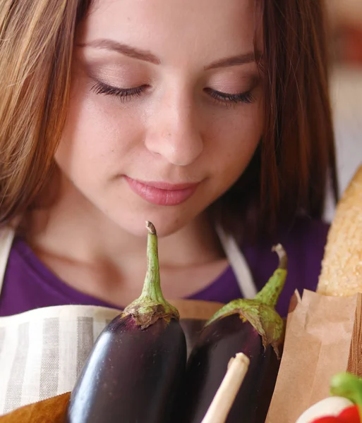 Jonge vrouw met boodschappentas met groenten Staande in de keuken — Stockfoto