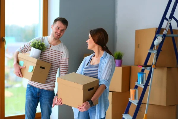 Feliz jovem casal desembalagem ou embalagem caixas e se mudar para uma nova casa — Fotografia de Stock