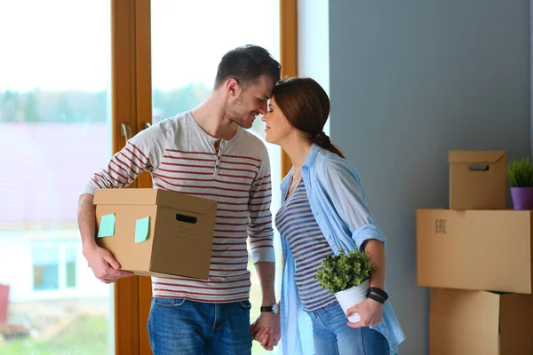 Feliz jovem casal desembalagem ou embalagem caixas e se mudar para uma nova casa — Fotografia de Stock