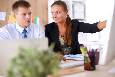 Moda tasarımcıları stüdyoda çalışıyor. Masanın üzerinde oturuyorlar.