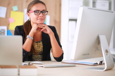 Moda tasarımcıları stüdyoda çalışıyor. Masanın üzerinde oturuyorlar.