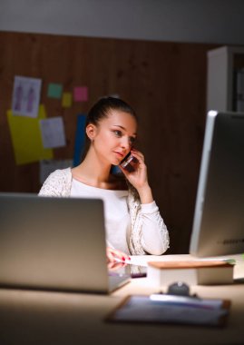 Ofiste çalışan genç bir kadın, masada oturuyor.