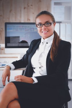 Ofiste çalışan genç bir kadın, masada oturuyor.