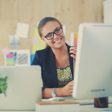 Moda tasarımcıları stüdyoda çalışıyor. Masanın üzerinde oturuyorlar.