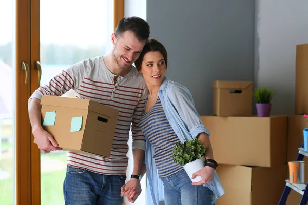 Feliz jovem casal desembalagem ou embalagem caixas e se mudar para uma nova casa — Fotografia de Stock