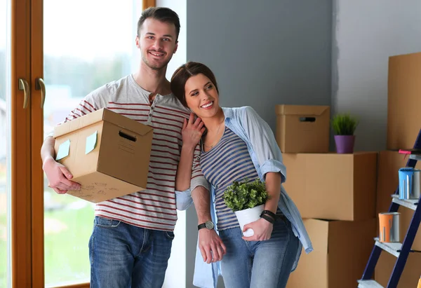 Feliz jovem casal desembalagem ou embalagem caixas e se mudar para uma nova casa — Fotografia de Stock