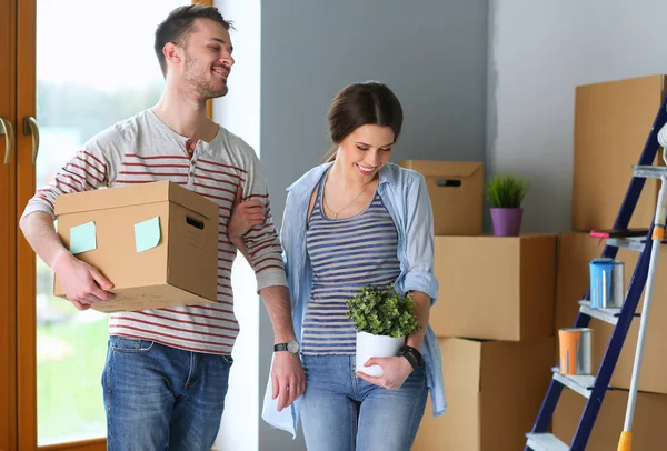 Feliz jovem casal desembalagem ou embalagem caixas e se mudar para uma nova casa — Fotografia de Stock