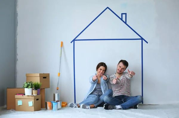 Couple sitting in front of painted home on wall — Stock Photo, Image