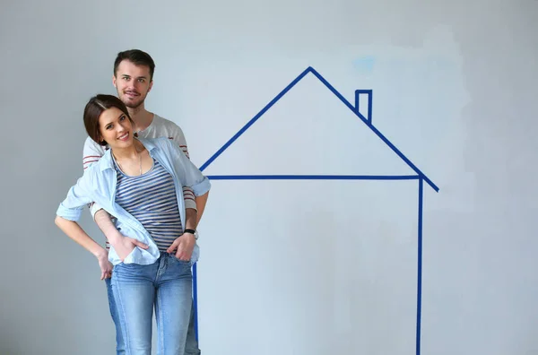 Couple standing in front of painted home on wall — Stock Photo, Image