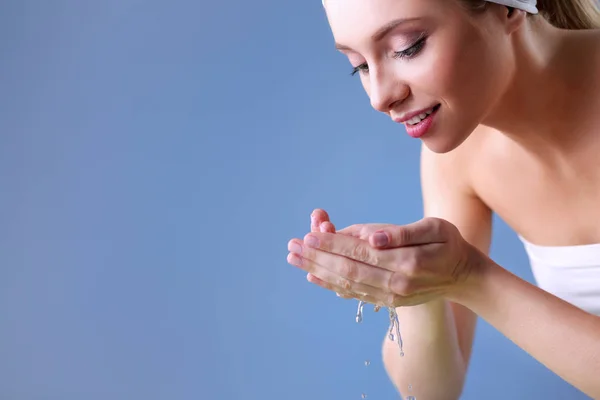 Young female washing her face with clear water