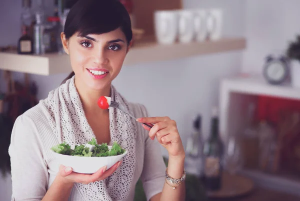 Ung kvinna äter färsk sallad i modernt kök — Stockfoto