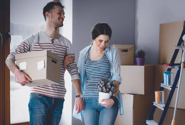 Feliz jovem casal desembalagem ou embalagem caixas e se mudar para uma nova casa — Fotografia de Stock