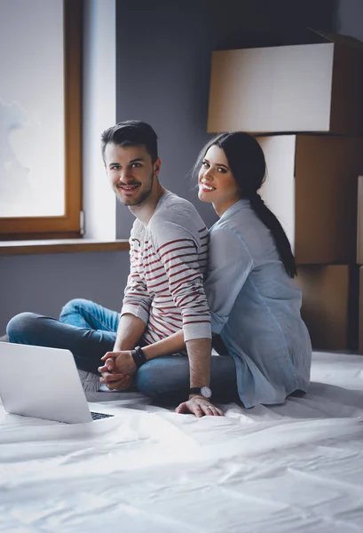 Молодая пара, сидящая на полу своей новой квартиры — стоковое фото