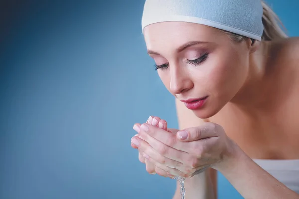 Young female washing her face with clear water