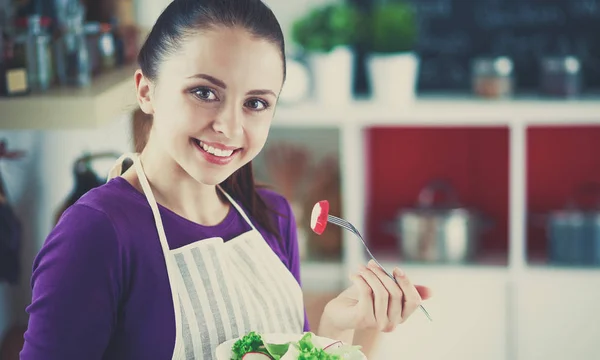 Jovem mulher comendo salada fresca na cozinha moderna — Fotografia de Stock