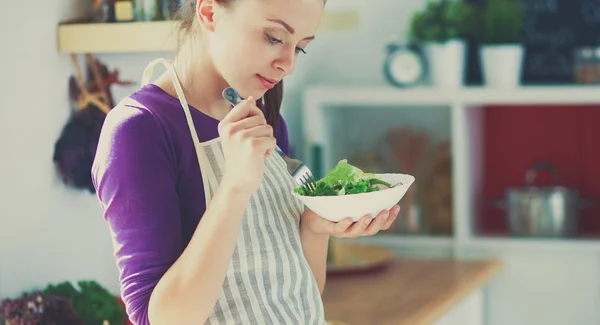 Young woman eating fresh salad in modern kitchen — Stock Photo, Image