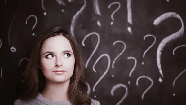 Giovane ragazza con punto interrogativo su uno sfondo grigio — Foto Stock