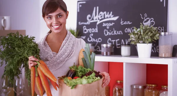 Gelukkig jong vrouw houden bos van wortelen in keuken — Stockfoto