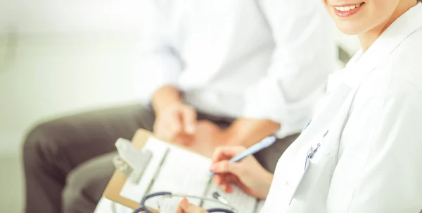 Fechar-se de belo médico feminino preenchendo um formulário com paciente no fundo . — Fotografia de Stock