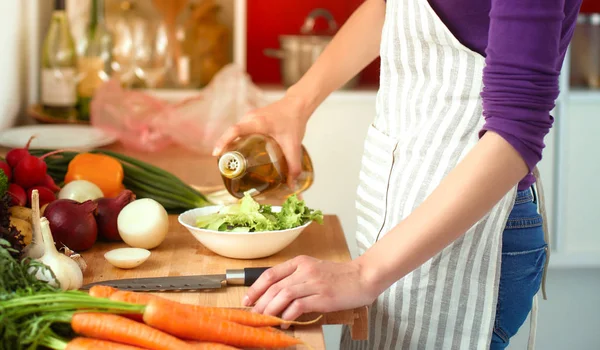 Mujer joven cortando verduras en la cocina — Foto de Stock