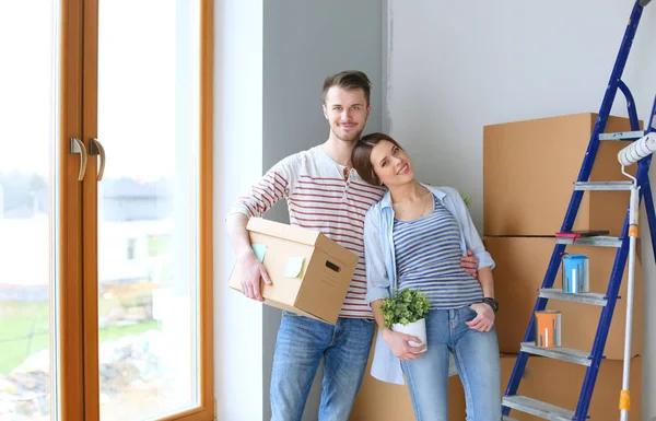 Feliz jovem casal desembalagem ou embalagem caixas e se mudar para uma nova casa — Fotografia de Stock