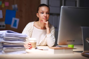 Ofiste çalışan genç bir kadın, masada oturuyor.