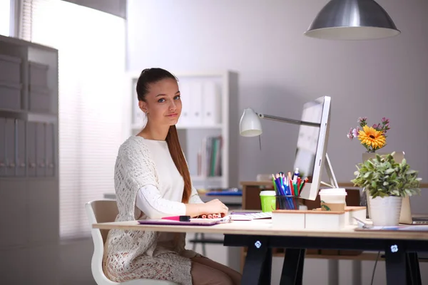 Young woman working in office, sitting at desk