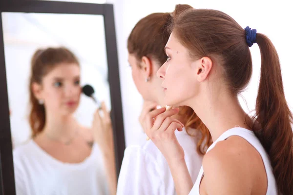 Krásné dívky při pohledu do zrcadla a použití kosmetiky s velkým štětcem — Stock fotografie