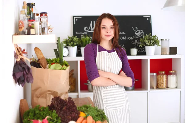 Onun mutfak masa alışveriş torbaları ile yakın duran genç kadın