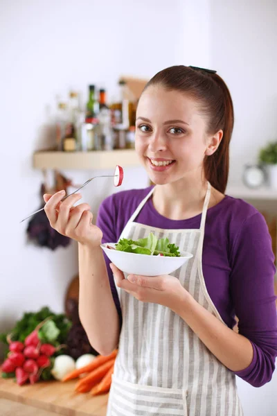 Young woman eating fresh salad in modern kitchen — Stock Photo, Image