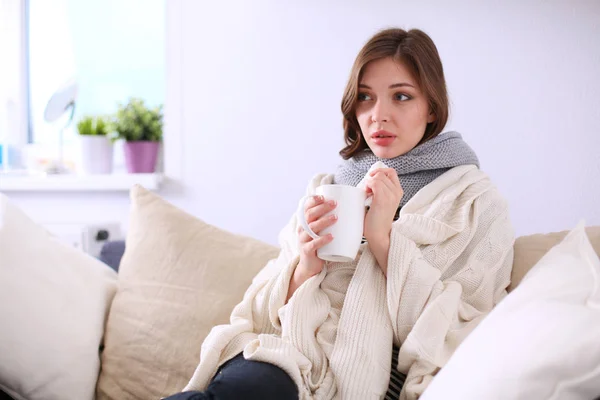 Portrait of a sick woman blowing her nose while sitting on the sofa — Stock Photo, Image