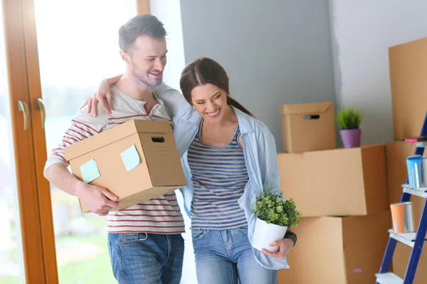 Feliz jovem casal desembalagem ou embalagem caixas e se mudar para uma nova casa — Fotografia de Stock