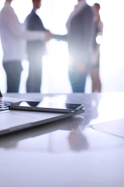 Laptop auf dem Schreibtisch, Geschäftsleute im Hintergrund — Stockfoto