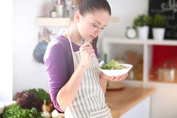 Young woman eating fresh salad in modern kitchen — Stock Photo, Image