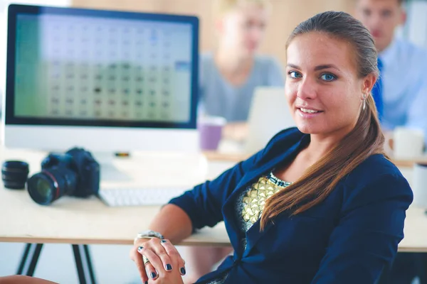 Молодая женщина работает в офисе, сидит за столом с папкой — стоковое фото