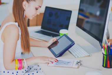 Ofiste çalışan genç bir kadın, masada oturuyor.