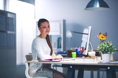 Ofiste çalışan genç bir kadın, masada oturuyor.